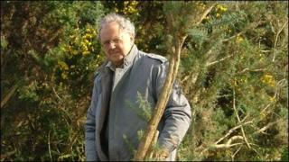 Dafydd Wyn Wiliam yn torri eithin ger cofgolofn y Morrisiaid ym Mhentre-eiriannell, Ynys Môn. Llun trwy garedigrwydd JR Williams ar ran Cymdeithas Morrisiaid Môn