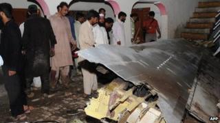 Pakistani villagers look at the plane's wreckage