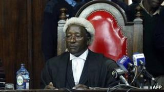 Nairobi, KENYA: Kenyan policemen watch over the shoulders of Justice Joseph Gregory Nyamu (R) and Rosalyne Wendo 15 November 2005 in Nairobi High Court. Supporters of the NO campaign crowded the court where High Court Judges rejected an attempt to stop the 21 November