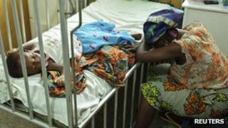 A mother sits next to her daughter who is in hospital with malaria and diarrhoea, 25 April 2012