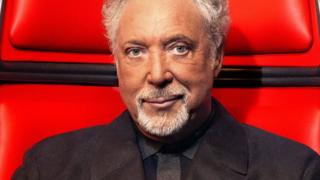 Sir Tom Jones sits in a big red chair on the set of The Voice UK.