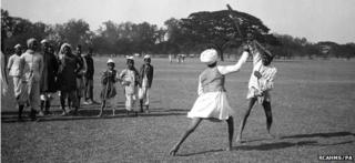 Two men stick dancing with onlooking crowd in Maidan, Calcutta