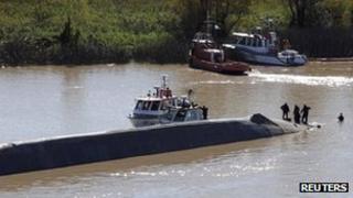 Rescuers climb on the capsized Argentine ship on the River Paraguay