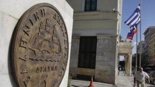 A man makes his way next to a replica of a one drachma coin outside the Athens Town Hall