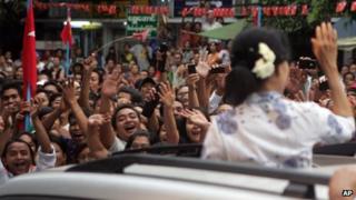A crowd of supporters surround a car carrying pro-democracy leader Aung Sung Suu Kyi in Rangoon, Burma