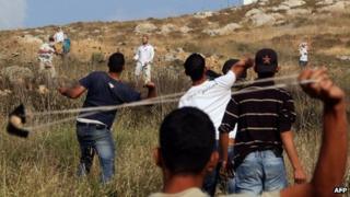Palestinians from the village of Asira al-Qubliya throw stones at young settlers from Yitzhar, who are also throwing stones