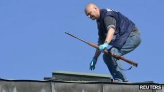 A police officer finds the rifle used by a gunman from a rooftop in a Finnish town centre in Hyvinkaa May 26, 2012