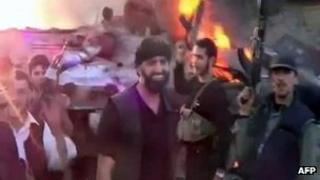 Screengrab of online video purportedly showing Syrian rebels brandishing their weapons in front of a burning tank (2 June 2012)