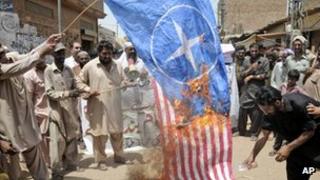 Pakistani protesters burn representations of US and NATO flags during a demonstration to condemn U.S. drone strikes in the tribal areas, in Multan, Pakistan