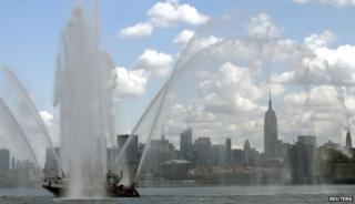 Горизонт Нью-Йорка и Эмпайр Стейт Билдинг видны под брызгами от пожарной лодки