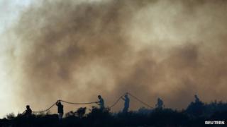 Firefighters and volunteers try to extinguish a forest fire at Thymari coastal village, 40 km (25 miles) southeast of Athens