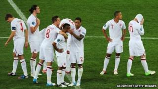 The England football team console Ashley Cole on the pitch in Kiev as his penalty is saved by Italy's goalkeeper
