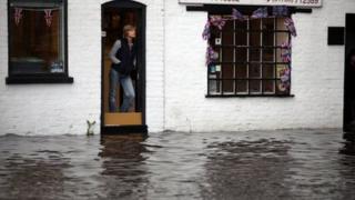 Работники магазина смотрят на внезапное наводнение в стаффордширской деревне Пенкридж