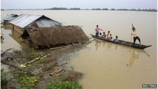 Flood-affected local residents move to safer places on a boat next to their damaged huts after heavy rains at Jajimukh village in the northeastern Indian state of Assam June 27, 2012