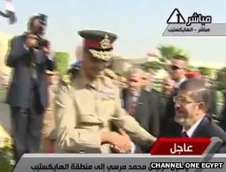 Field Marshal Hussein Tantawi shakes hands with new Egyptian President Mohammed Mursi (video grab from Egyptian public TV broadcaster Channel One)