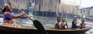 Children sit in a canoe with their mother as she navigates through waterways in the Makoko slum in Lagos, Nigeria, on 29 September 2011