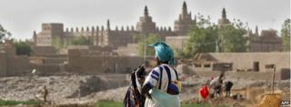 This photo taken on 8 February 2005, shows a woman and her child resting, with the Great Mosque of Djenne in the background in Mali