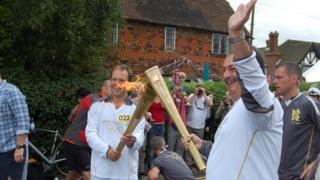Torchbearers stage the "torch kiss" as the flame is handed over