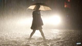 A woman walks on a flooded street during heavy rainfall in Beijing, 21 July 2012