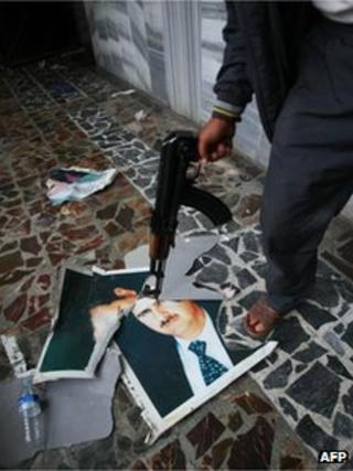 FSA fighter near Turkish border holding gun to picture of President Assad (22 July)