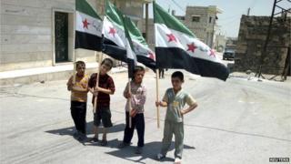 Four children holding up Syria flags