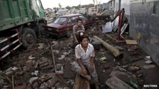 Fangshan residents sit amidst debris and damaged vehicles