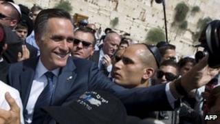 Mitt Romney waves at a camera by the Wailing wall