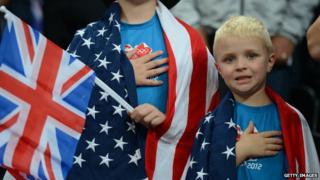 Two children draped in American flags, with their hands on their hearts