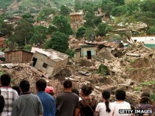 Жители Тегусигалапы смотрят на некоторые дома, разрушенные в результате оползня на Серро-эль-Берринче