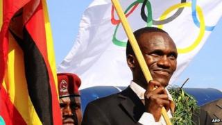 Ugandan Olympics marathon gold winner Stephen Kiprotich holds a flag on arrival to Entebbe International Airport on 15 August 2012