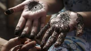A girl gets her hands painted with henna in preparation for Eid al-Fitr