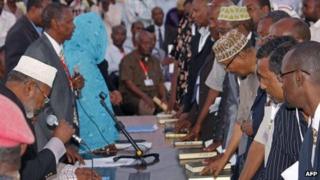 Members of Somalia's new parliament place their hands on the Koran as they are sworn in at Mogadishu's international airport