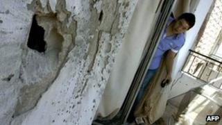A Lebanese man looks at a hole on a building following a rocket-propelled grenade attack in the northern Lebanese city of Tripoli (22 August 2012)