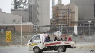 Workers in a truck pass on August 27, 2012 by the main entrance of the Lonmin platinum mine in Marikana