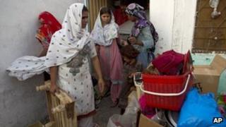 Pakistani Christian women collect their belongings to leave their home in a suburb of Islamabad, Pakistan on Thursday, Aug. 23, 2012.