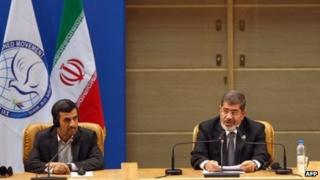 Egyptian President Mohammed Mursi (R) makes his speech at the NAM summit, as Iranian President Mahmoud Ahmadinejad listens