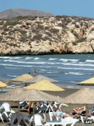 People sunbathe on a beach in Al Hoceima in north Morocco, as the Spanish sovereign territory of Isla de Tierra is seen in the background on September 4, 2012.