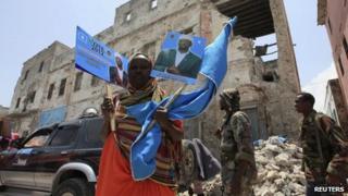 A woman holds up election campaign posters of Somalia"s President Sheikh Sharif Ahmed in Mogadishu, September 9, 2012.