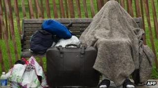 A homeless man protects himself from the rain on a bench near the White House in Washington on 14 May 2012
