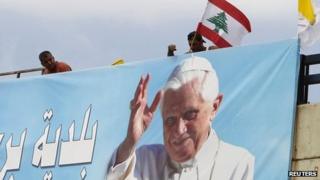 Worker places Lebanese flag on billboard depicting Pope Benedict XVI at airport road in Beirut. 13 Sept 2012