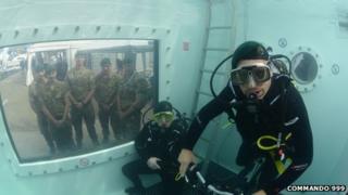 Marines watch Chris Sirett and Brian Stokes through a window as they attempt the underwater challenge