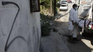 Forensic technicians remove a body from a crime scene near a wall spray painted with the "Z" symbol of the Zetas drug cartel, in Monterrey.