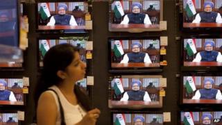 Индийская девушка наблюдает за тем, как премьер-министр Манмохан Сингх обращается к народу с докладом о текущей экономической ситуации в стране, в демонстрационном зале электроники в Мумбаи, Индия, в пятницу, 21 сентября 2012 года.