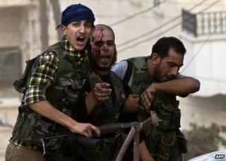 An injured rebel fighter is helped to safety in Aleppo, Syria, 27 September