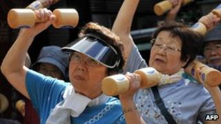 Elderly people work out with wooden dumb-bells in Tokyo, Japan