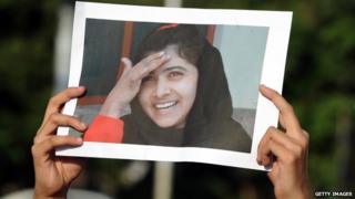 Someone holding a picture of Malala Yousafzai.