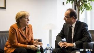 German Chancellor Angela Merkel talks with French President Francois Hollande ahead of an EU summit in Brussels