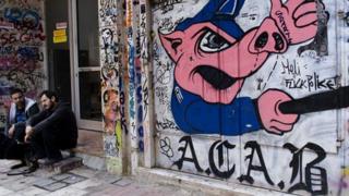 Афиняне сидят перед антиправительственными граффити