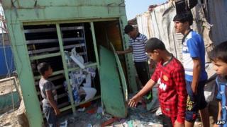 Iraqis inspect the site of a bomb attack at Al-Bawiya market, in the east Baghdad district of Maamal
