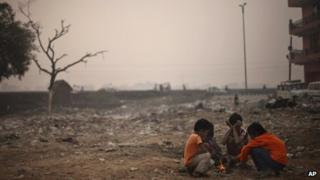 Индийские мальчики сидят у небольшого костра, поскольку утреннее солнце окутано слоем смога, вызванным смесью загрязнения и тумана в Нью-Дели, Индия, среда, 7 ноября 2012 г.